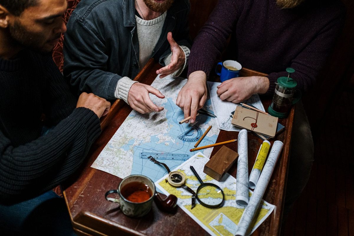 People plotting a route on paper charts with a magnifying glass and dividers