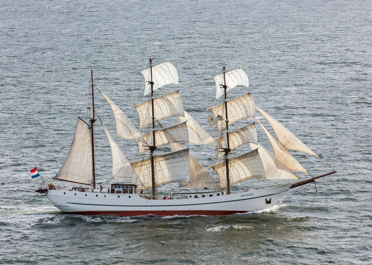A tall sailing ship under full sail on a grey sea